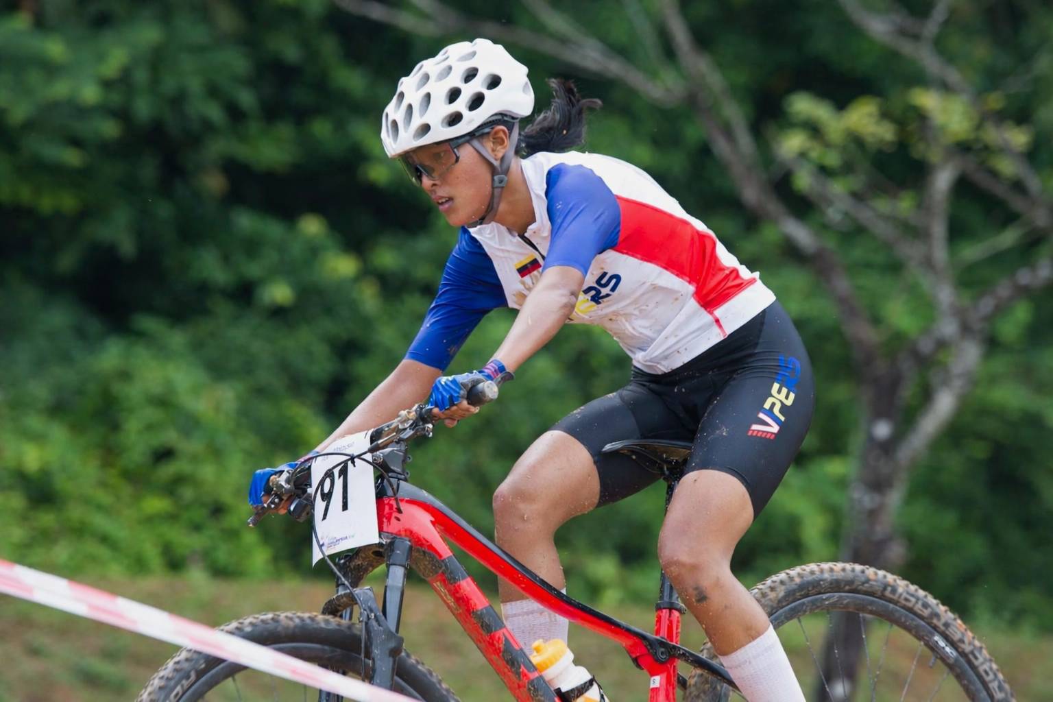 Elite female mountain bike rider climbing a steep trail during an off-road ride.
