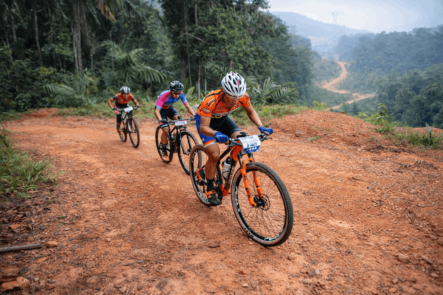 Four mountain bikers riding technical trail terrain with carbon MTB wheels.